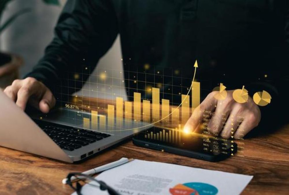 A financial consultant discussing cost-saving strategies with a business owner, analyzing reports and data on a laptop to improve financial efficiency.