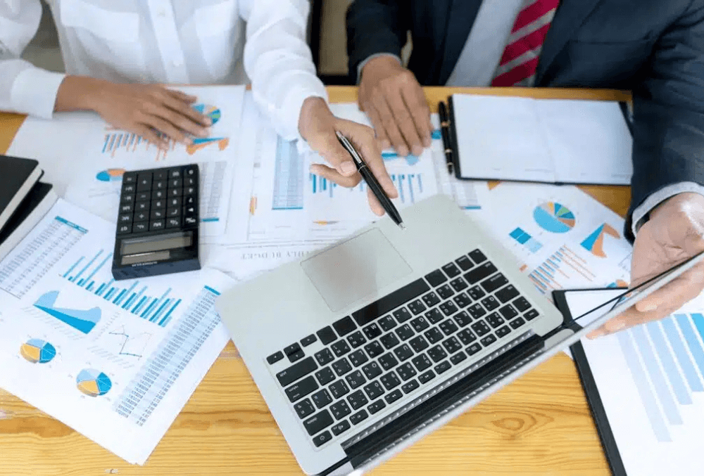 A franchise owner reviewing startup costs and financial projections with a consultant, discussing strategies to reduce expenses and improve profitability.
