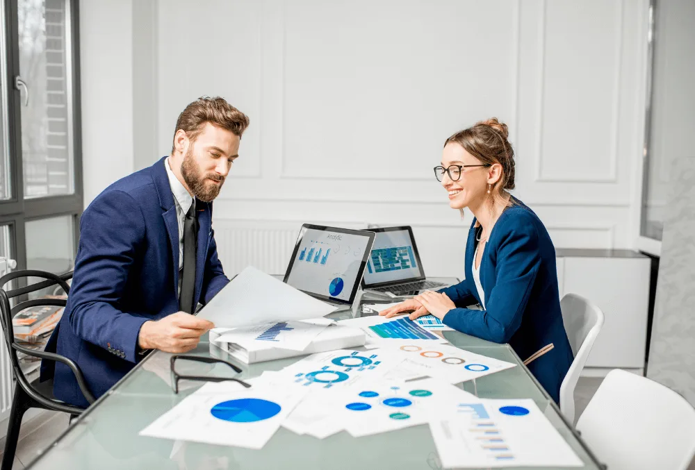 Franchise business owner analyzing financial reports, using accounting software, and discussing cost strategies with an advisor.