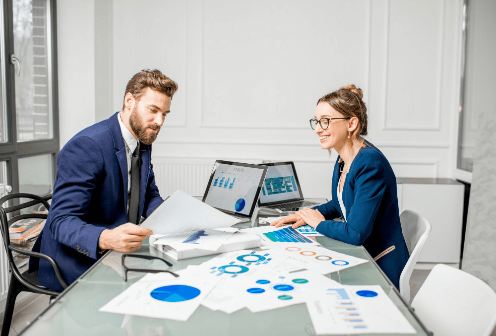 Franchise business owner analyzing financial reports, using accounting software, and discussing cost strategies with an advisor.